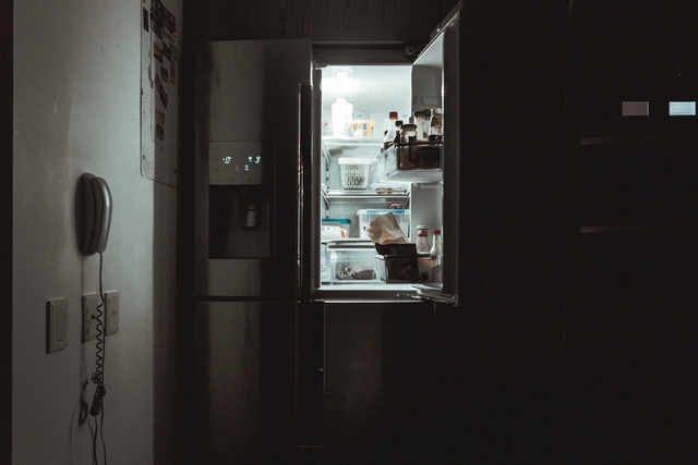 Odprta vrata hladilnika v temni sobi